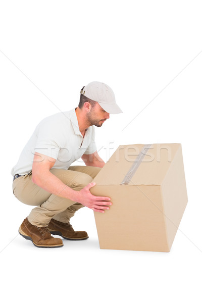Delivery man crouching while picking cardboard box  Stock photo © wavebreak_media