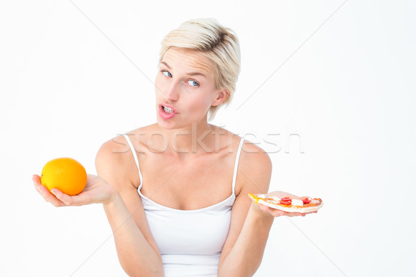 Pretty woman deciding between pizza and an orange Stock photo © wavebreak_media