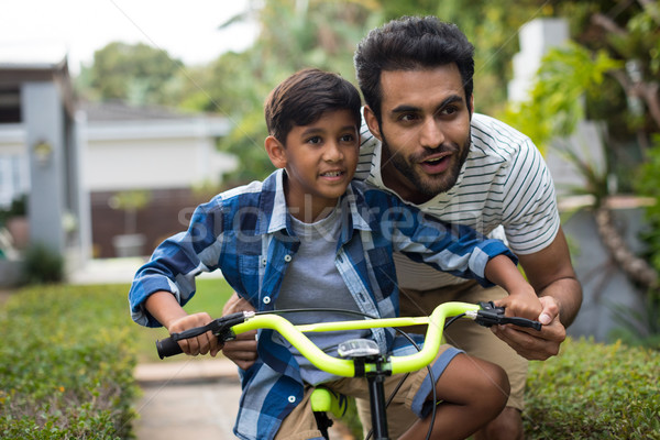 Father looking away while assisting son for cycling Stock photo © wavebreak_media