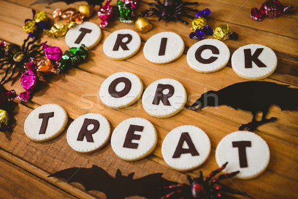 Cookies with trick or treat text by decorations and chocolates on table Stock photo © wavebreak_media