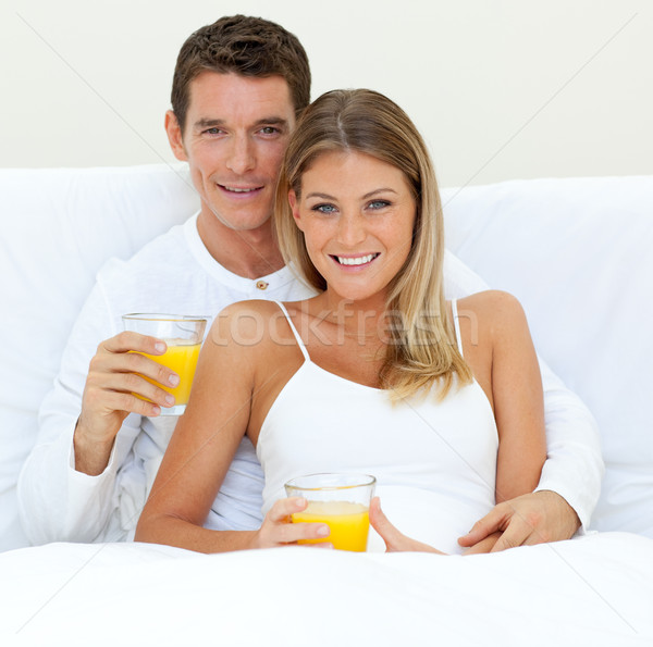 Happy couple drinking orange juice lying on their bed Stock photo © wavebreak_media