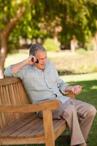 Stock photo: Mature man phoning in the park