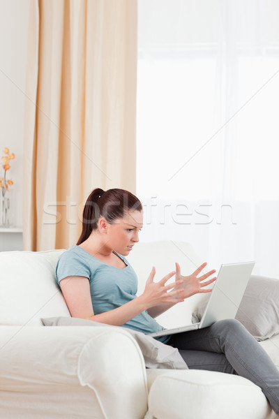Good looking upset woman gambling with her computer while sitting on a sofa in the living room Stock photo © wavebreak_media