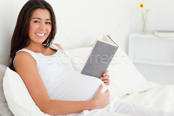 Beautiful pregnant woman reading a book while lying on a bed at home Stock photo © wavebreak_media