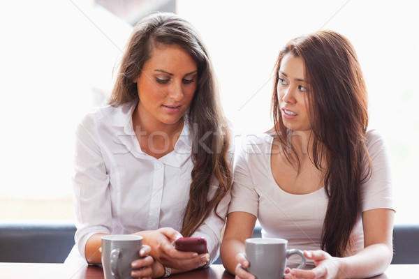 Beautiful friends looking at a smartphone while having a tea Stock photo © wavebreak_media