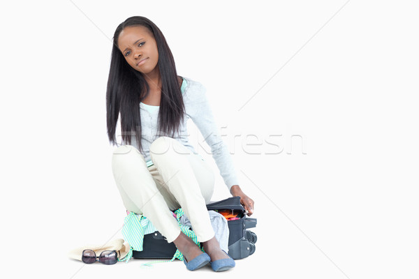 Stock photo: Young woman can't get her suitcase closed against a white background