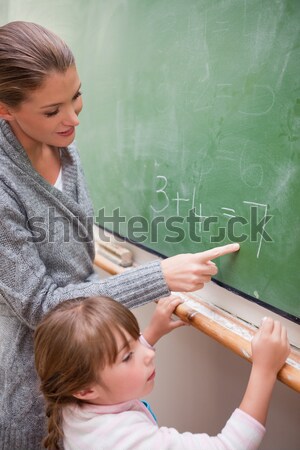 Schoolteacher helping a schoolboy doing an addition on a blackboard Stock photo © wavebreak_media