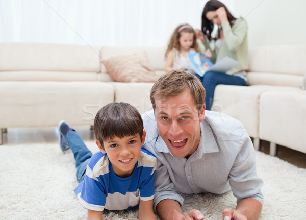 Stock photo: Dad and son lying on the carpet with mom and daughter behind them
