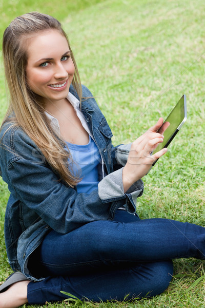 Young happy girl looking at the camera while touching her tablet pc in a parkland Stock photo © wavebreak_media