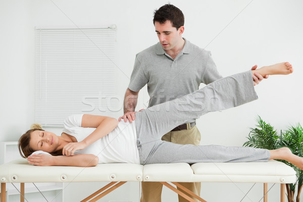Serious practitioner rising the leg of his patient in his room Stock photo © wavebreak_media