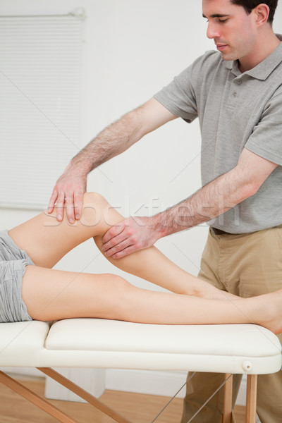 Serious brunette doctor holding the knee of his patient in a room Stock photo © wavebreak_media