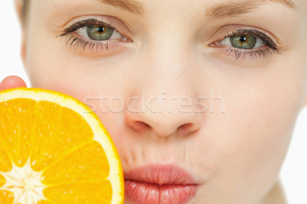 Close up of a woman placing an orange near her mouth against white background Stock photo © wavebreak_media