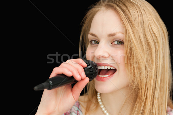 Young blond-haired woman singing against black background Stock photo © wavebreak_media