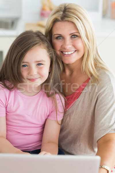 Woman and daughter sitting while smiling in the kitchen with a laptop Stock photo © wavebreak_media