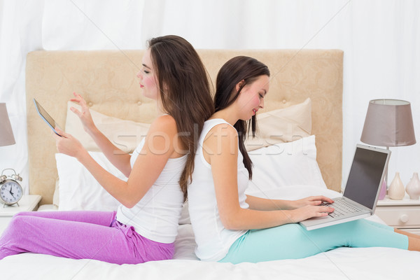 Pretty friends using their technology on bed Stock photo © wavebreak_media