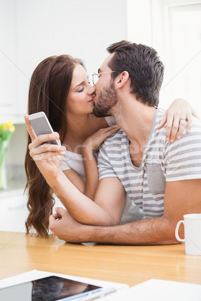 Young man using smartphone while girlfriend kisses him Stock photo © wavebreak_media