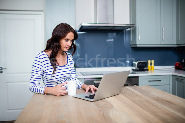 Stock photo: Young woman working on laptop while sitting at table