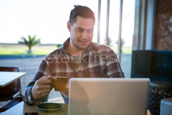 Smiling man using laptop while having coffee Stock photo © wavebreak_media