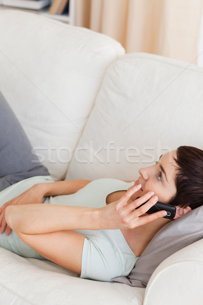 Portrait of a calm brunette calling while lying on a sofa in her living room Stock photo © wavebreak_media
