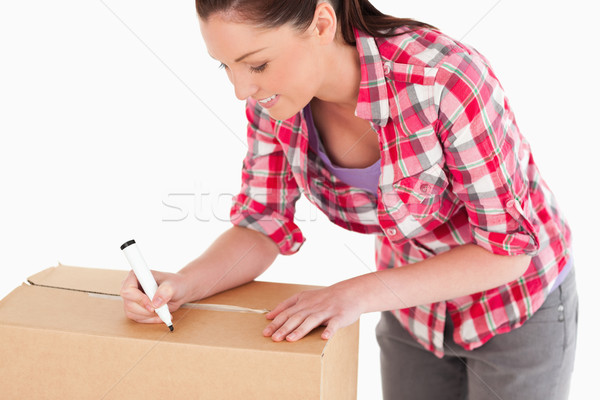 Portrait of a beautiful woman writing on cardboard boxes with a marker while standing against a whit Stock photo © wavebreak_media