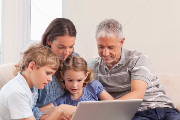 Happy family sitting on a sofa using a laptop in a living room Stock photo © wavebreak_media