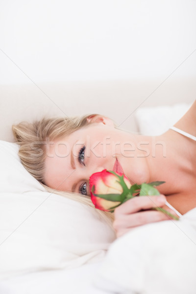 Blue eyed woman smelling a rose in he bed Stock photo © wavebreak_media