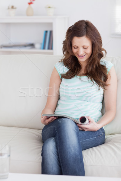 Stock photo: Woman smiling while reading a magazine in a living room