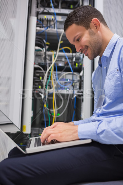 Stock photo: Man using laptop in front of servers in data center