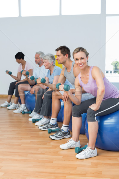 Class with dumbbells sitting on exercise balls in gym Stock photo © wavebreak_media