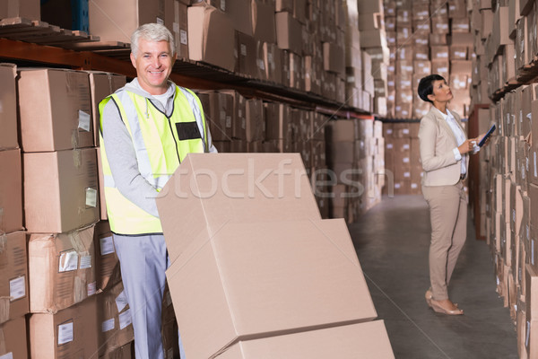 Stock photo: Warehouse worker moving boxes on trolley