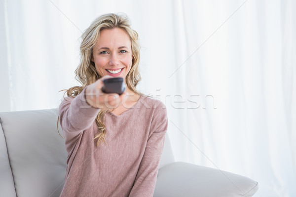 Happy blonde on couch changing tv channel Stock photo © wavebreak_media