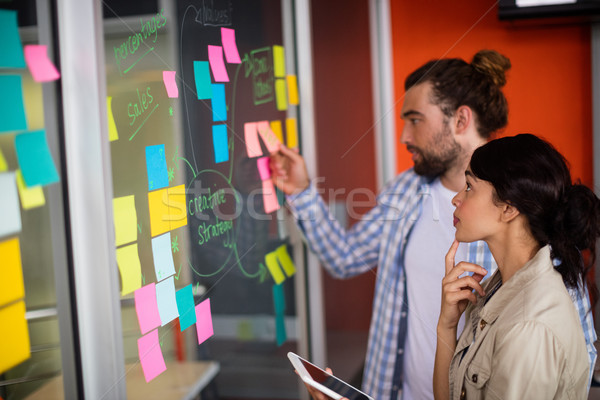 Male and female executives looking at sticky notes Stock photo © wavebreak_media