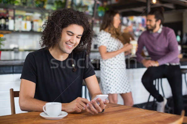 улыбаясь молодым человеком мобильного телефона сидят ресторан таблице Сток-фото © wavebreak_media