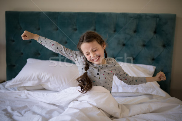 Girl stretching her arms while waking up in bedroom Stock photo © wavebreak_media