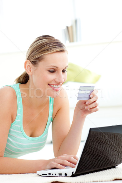 Captivating young woman using her laptop holding a card in the living room Stock photo © wavebreak_media