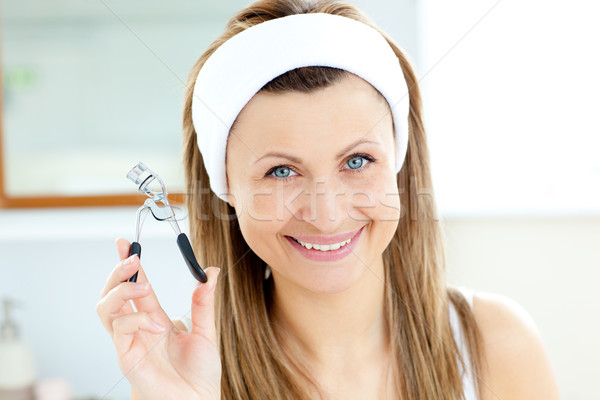 Smiling woman holding an eylash curler looking at the camera in the bathroom Stock photo © wavebreak_media