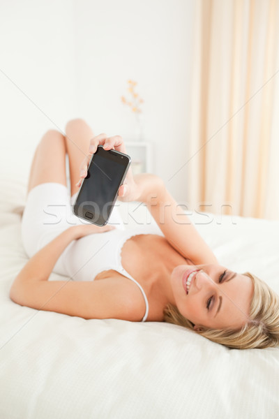 Portrait of a cute woman showing her smartphone in her bedroom Stock photo © wavebreak_media
