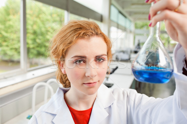 Cute science student holding a flask while looking at the camera Stock photo © wavebreak_media