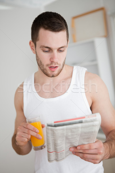 Portret młody człowiek czytania wiadomości pitnej sok pomarańczowy Zdjęcia stock © wavebreak_media