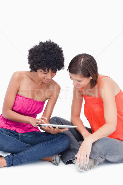 Stock photo: Beautiful teenagers attentively looking at a tablet PC against a white background
