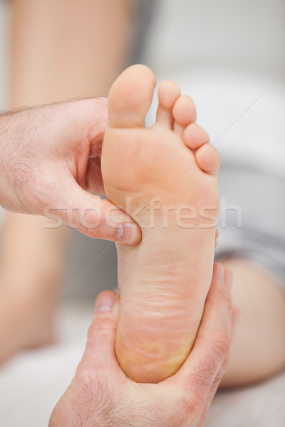 Doctor pressing the sole of a foot with his thumb in a room Stock photo © wavebreak_media