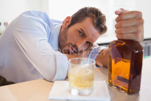 Drunk businessman clutching whiskey bottle looking at camera Stock photo © wavebreak_media