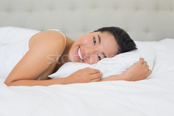 Smiling asian woman lying on bed Stock photo © wavebreak_media
