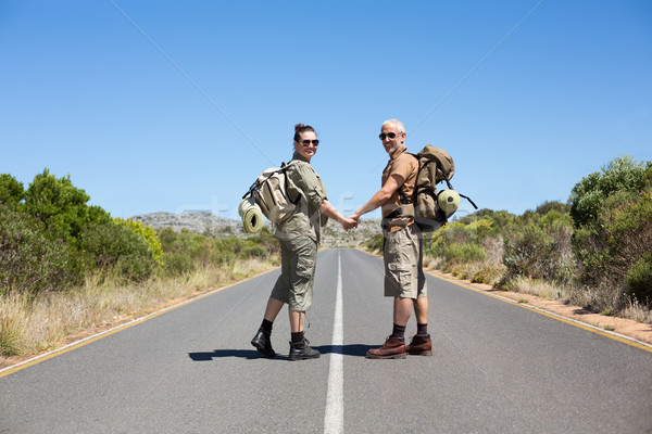 Hitch hiking couple holding hands on the road smiling at camera Stock photo © wavebreak_media