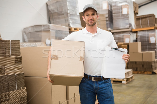 Delivery man with box and clipboard in warehouse Stock photo © wavebreak_media