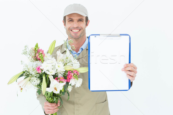 Happy delivery man holding bouquet and clipboard Stock photo © wavebreak_media