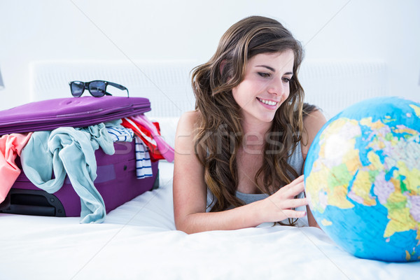 Woman with a suitcase and globe while lying on her bed Stock photo © wavebreak_media