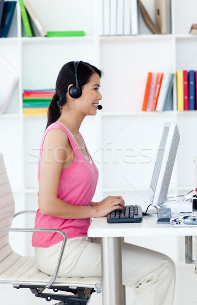 Stock photo: Serious businesswoman with headset on at a computer