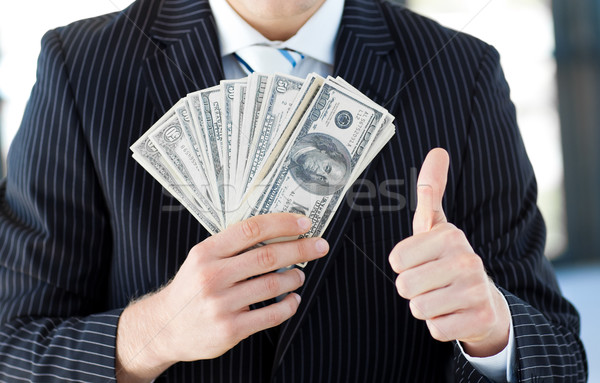 Businessman showing dollars with thumbs up Stock photo © wavebreak_media