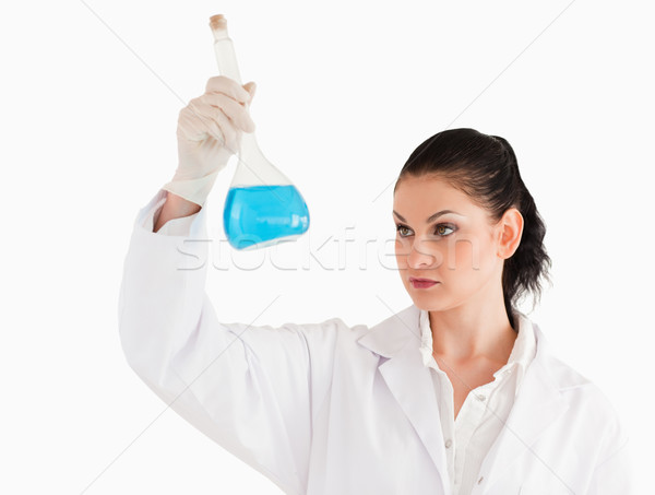 Stock photo: Dark-haired female scientist looking at a flask on a white background